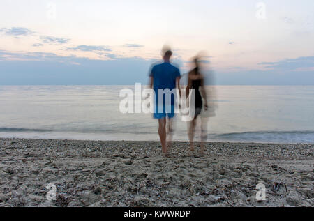 Paar silhouette halten sich an den Händen und laufen auf dem Strand bei Sonnenuntergang im Sommer Urlaub in Griechenland Stockfoto