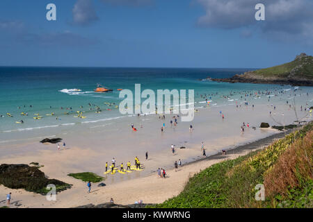 Ein Sommertag am Strand St Ives in Cornwall. Die RNLI lifeboat Patrouillen offshore während Surfers und Touristen die schönen sonnigen Bedingungen genießt. Stockfoto