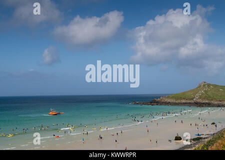 Ein Sommertag am Strand St Ives in Cornwall. Die RNLI lifeboat Patrouillen offshore während Surfers und Touristen die schönen sonnigen Bedingungen genießt. Stockfoto