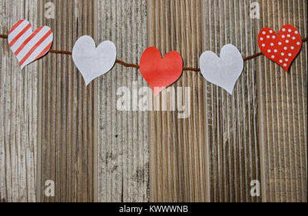 Rote und weiße Herzen hängen auf einer Linie vor Holz Stockfoto