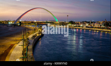 Blick auf das beleuchtete Fußgängerbrücke über Dubai Canal nach Sonnenuntergang Stockfoto