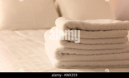 Hotel Schlafzimmer. Weißen flauschigen, gefaltete Handtücher, Bettwäsche Bettwäsche auf ordentlich Bett. Nahaufnahme, Details. Stockfoto