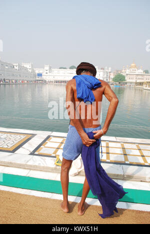 Ein Sikh Mann auch immer bereit in den Gewässern an der Sri Harmandir Sahib zu baden, wie die goldenen Tempel, Amritsar, Indien Stockfoto