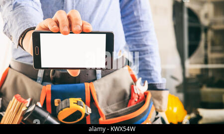 Arbeitnehmer mit einem Werkzeug Gürtel Holding ein Smartphone Stockfoto