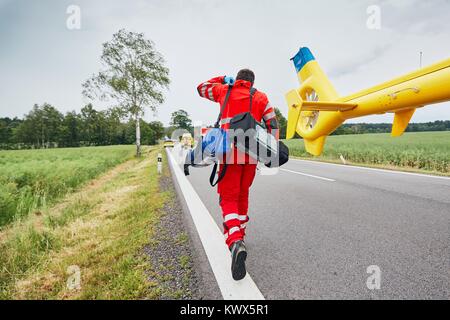 Arzt mit Defibrillator und andere Geräte, die von einem Hubschrauber. Teams der Emergency Medical Service sind die Reaktion auf einen Verkehrsunfall. Stockfoto