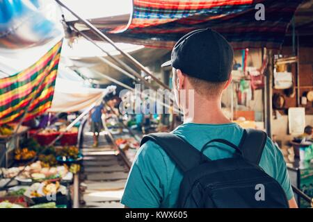 Junger Mann (touristische) wandern Markt entlang der Bahnstrecke zu öffnen. Maeklong Railway Markt in der Nähe von Bangkok in Thailand. Stockfoto