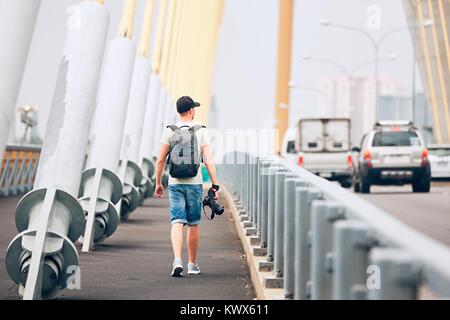 Junge Fotografen (Reisender) mit Foto Kamera zu Fuß auf die Brücke und auf der Suche nach Inspiration. Bangkok, Thailand Stockfoto