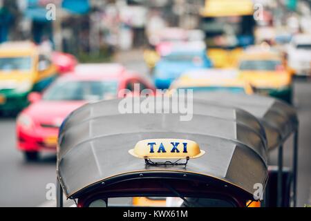 Taxi Schild auf der tuk tuk gegen Verkehr mit bunten Taxi Autos. Viel befahrenen Straße in Bangkok, Thailand Stockfoto