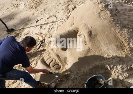 Sand Bildhauer arbeitet an einem Kopf in Sand auf der South Bank in London. Stockfoto