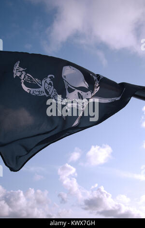 Piratenflagge mit totenkopf und gekreuzten knochen, fliegen in den Wind vor blauem Himmel. Stockfoto