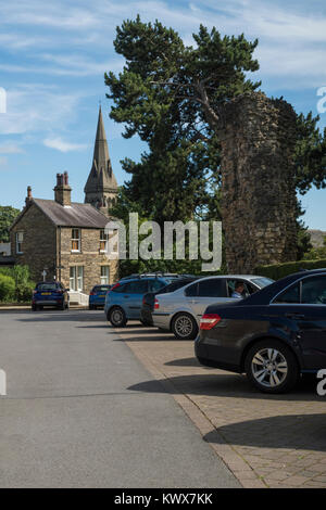 Autos im Stadtzentrum Parkplatz von Burgruinen auf sonnigen Sommertag geparkt, mit hohen Kirchturm hinaus - Knaresborough, North Yorkshire, England, UK. Stockfoto