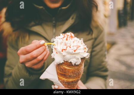 Trdelnik oder Trdlo mit Sahne in den Händen einer schönen Winter Mädchen in der Tschechischen Republik, Prag auf dem Weihnachtsmarkt. Stockfoto