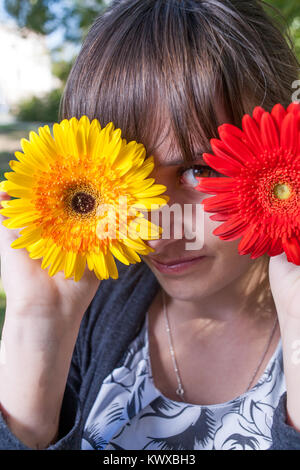 Hübsche Frauen, die ihre Augen mit frischen Blumen und genießen Sommer Bild vertikal Stockfoto