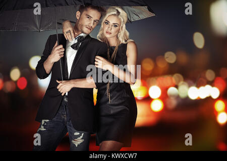 Intelligente Paare, die mit dem schwarzen Regenschirm Stockfoto