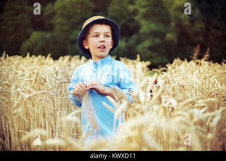 Süsser Boy unter goldenem Getreide Ohren ruhen Stockfoto