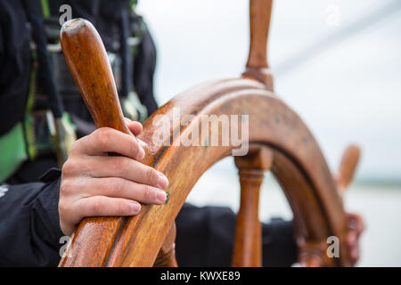 Eine junge Segler an die Spitze. Hände auf einem Segelschiffe Holz- Rad. Stockfoto