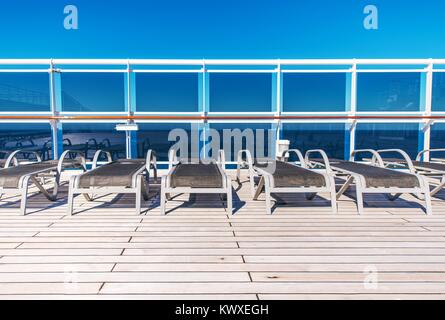 Kreuzfahrtschiff Sea Travel Concept mit Holz Liegestühle auf dem offenen Deck des Schiffes. Stockfoto