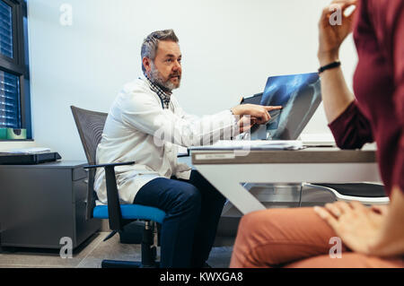 Arzt erklären medizinische Ergebnis Scannen an weiblichen Patienten in seiner Klinik. Medizin Praktiker x - ray zu Frau und Erörterung der Gesundheit Stockfoto