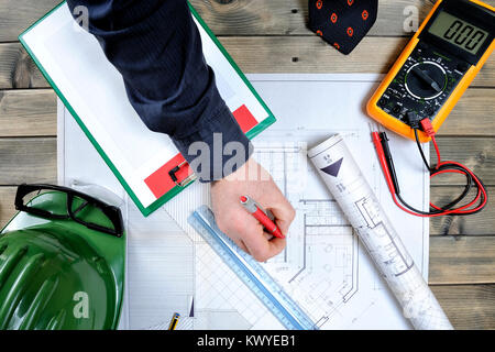 Von der Spitze eines Ingenieurs bei der Analyse der Gestaltung eines Wohnungsbau auf einem antiken Holztisch Schuß Stockfoto