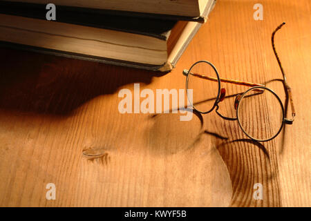 Sehr alte Brillen in der Nähe von zwei Bücher liegen auf schöne Holz- Hintergrund Stockfoto