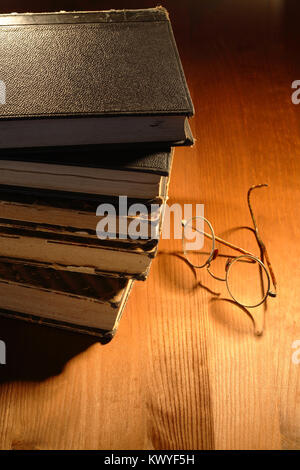 Sehr alte Brillen in der Nähe der Bücher liegen auf schöne Holz- Hintergrund Stockfoto