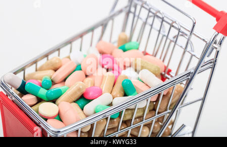 Trolley mit bunten Pillen auf weißem Hintergrund Stockfoto