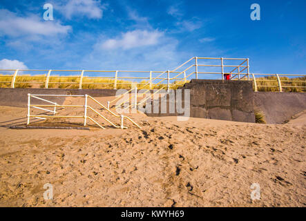 Wind-driven Sand aufgeschichtet gegen den Zugang zum Strand wenige Schritte von einem Meer Wand an der Aberavon Beach, South Wales, UK. Stockfoto