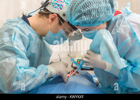 Gesundheitswesen, Medizin. Patienten mit Zahnarzt in Maske mit Lupe Fernglas in einer Zahnarztpraxis. Stockfoto