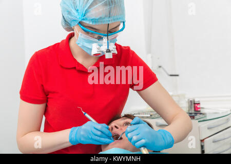 Foto von einem Zahnarzt in der Maske mit Lupe Fernglas Heilung eines Patienten Zähne. Madical Büro Stockfoto