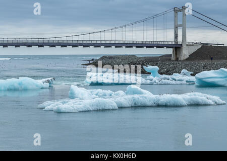 Eisbergen auf der Gletscherlagune Jokulsarlon kalben aus dem Gletscher Breiðamerkurjökull, im Südosten von Island, und fließt zum Meer unter einer Brücke Stockfoto
