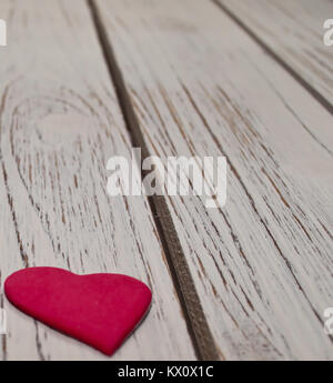 Eine Nahaufnahme von einem kleinen roten Herzen Festlegung auf eine weiße Holztisch Stockfoto