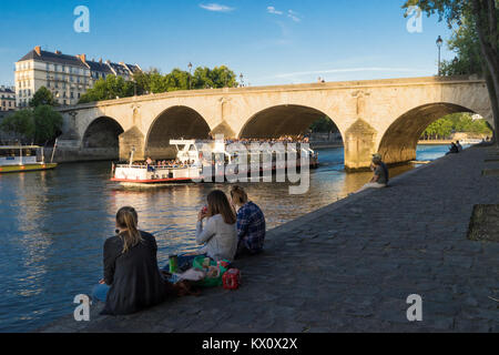 Frankreich, Paris (75), Frau picknicken auf dem Quai de Bourbon mit der Pont Marie hinter Stockfoto