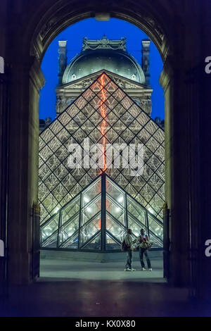 Frankreich, Paris (75), Museum Louvre bei Nacht mit Pyramide beleuchtet. Zwei Afrikanische tchotchke Verkäufer. Stockfoto