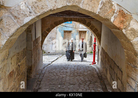 Ältere Paare wandern in der Alten Gasse mit einem Torbogen, in Gaziantep, Türkei. Stockfoto