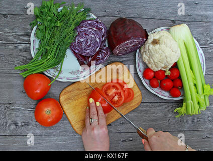 Weibliche Hände Schneiden von Gemüse auf einem Holztisch Stockfoto