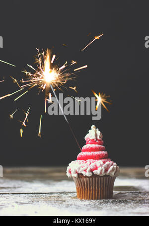 Cupcake mit Red swirl Zuckerguss und Wunderkerze, Christmas cupcake Dekoration Stockfoto