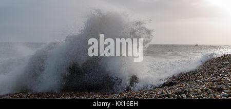 Storm wave schlagen Strand mit Fischerbooten in der Ferne in Selsey, West Sussex, Großbritannien Stockfoto