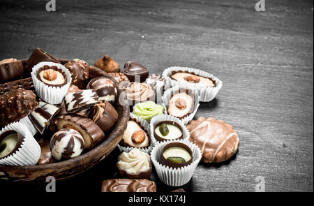 Bonbons Schokolade in eine Schüssel geben. Auf der schwarzen Tafel. Stockfoto