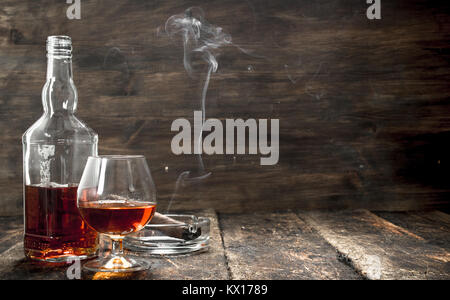Französischer Cognac mit einem rauchenden Zigarre. Auf einer hölzernen Hintergrund. Stockfoto