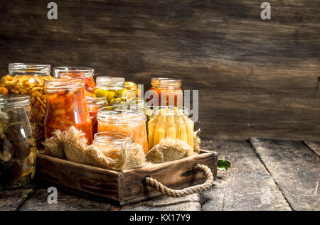 Anders haltbar gemacht Gemüse aus Gemüse und Pilzen, die in Gläsern. Auf einer hölzernen Hintergrund. Stockfoto