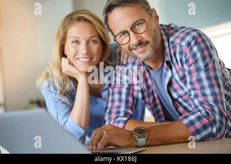 Älteres Ehepaar mit Laptop zu Hause angeschlossen Stockfoto