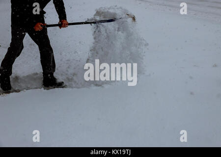 Mann mit Schneeschaufel reinigt die Bürgersteige im Winter. Winter. Man Schnee Räumen mit einer Schaufel Stockfoto