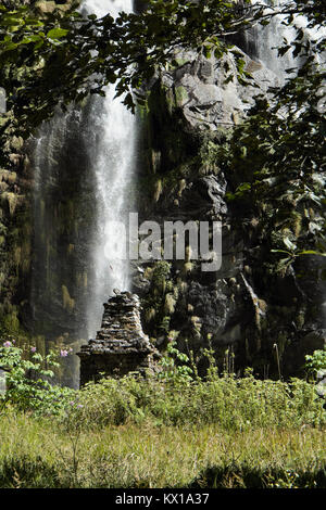 Wasserfall in den Bergen in Nepal unter grünen Pflanzen mit alten buddhistischen chorten Denkmal Stockfoto