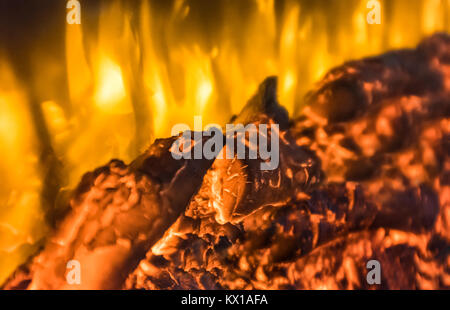 Protokolle glühen und Brennen mit goldenen Flammen in einer Glasfront Imitation elektrische Wand Feuer, Kamin. Hintergrundbild für Feuer und Wärme Stockfoto