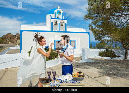 Junges Paar essen Hochzeitstorte im Hintergrund der Gebäude der Kirche Stockfoto