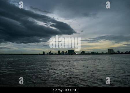 Phnom Penh Dämmerung Sonnenuntergang, wie vom Mekong und Tonle Sap Fluss gesehen, und die aufstrebenden Wolkenkratzer. Monsunzeit und Regen Wolken der Stadt Stockfoto