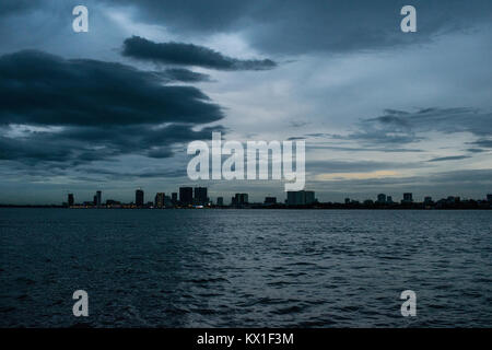 Phnom Penh Dämmerung Sonnenuntergang, wie vom Mekong und Tonle Sap Fluss gesehen, und die aufstrebenden Wolkenkratzer. Monsunzeit und Regen Wolken der Stadt Stockfoto