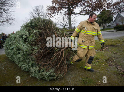 Richmond, Kanada. 6. Januar, 2018. Ein Feuerwehrmann trägt einen Baum für das Recycling im Rahmen des jährlichen Weihnachtsbaum chipping Veranstaltung in Richmond, Kanada, Jan. 6, 2018. Gesammelten Bäume werden abgebrochen und für Sie zu Ressourcen zugeführt werden. Credit: Liang Sen/Xinhua/Alamy leben Nachrichten Stockfoto