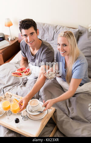 Glückliches junges Paar mit Frühstück im Bett Stockfoto