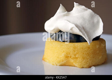 Frische süße Blaubeeren auf einem mini Kuchen abgerundet mit flauschigen Schlagsahne Stockfoto